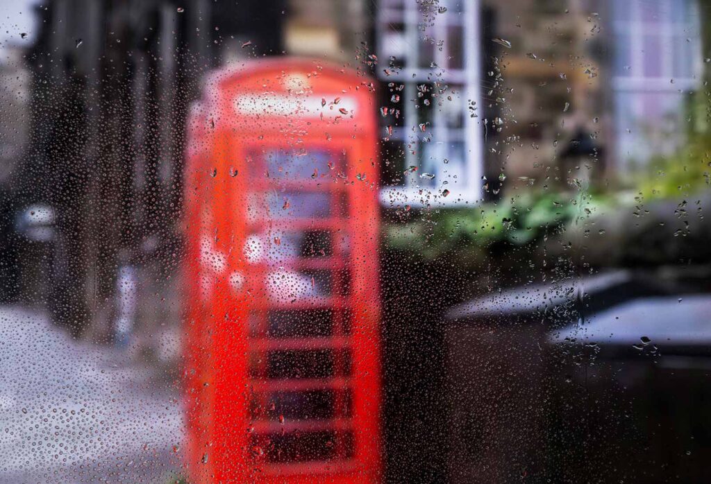 An image showing London's rainy weather through a rainy glass and a red telephone box can be seen.