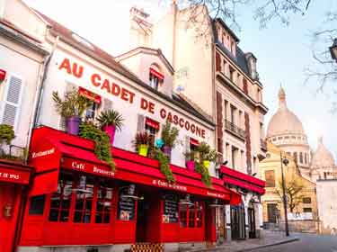 Cafe in Montmartre, Paris with Sacre Coeur Basilica dome on the background