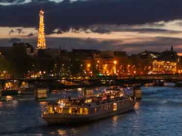 River Seine cruise in Paris, nighttime with illuminated Eiffel Tower on the background